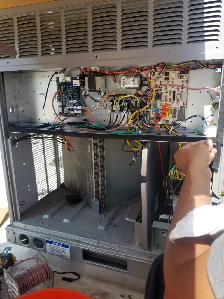 HVAC technician working on the wiring inside an RTU or rooftop unit.
